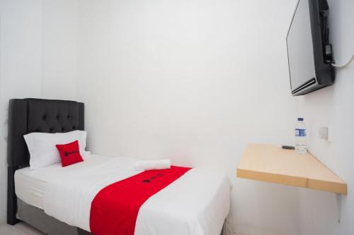 1 dormitorio con cama blanca y almohada roja en RedDoorz at Jalan Bangau Palembang en Palembang