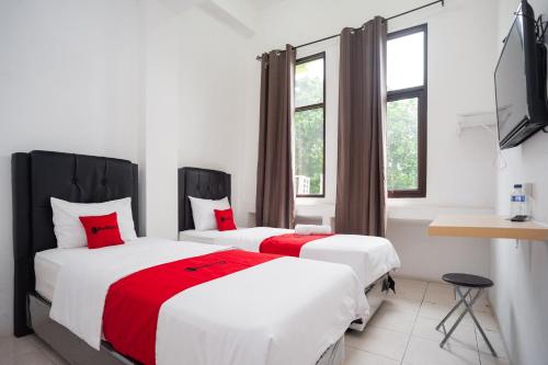 1 dormitorio con 2 camas y almohadas rojas en RedDoorz at Jalan Bangau Palembang en Palembang