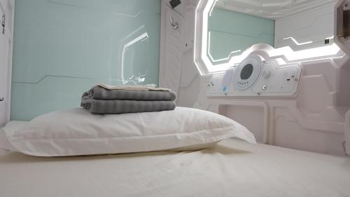 a hospital bed with a pillow and a washing machine at Apollo Capsule Hotel in Ende