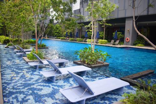 - une piscine avec des chaises longues blanches en face d'un bâtiment dans l'établissement Star Sky Park KLCC, à Kuala Lumpur