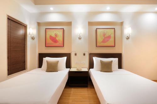 two twin beds in a room with two lamps at Lemon Tree Premier, Ulsoor Lake, Bengaluru in Bengaluru