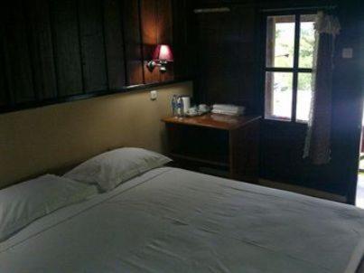 a bedroom with a bed and a window and a window at Ue Datu Cottages in Tentena