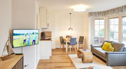 ein Wohnzimmer mit einem Sofa und einem TV in der Unterkunft Ferienwohnung mit Meerblick Grimmershörnbucht in Cuxhaven