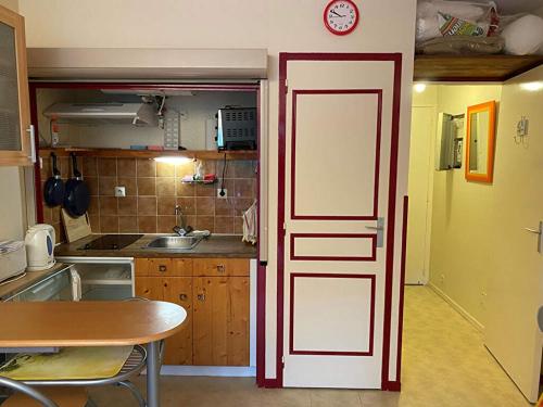 une cuisine avec une porte rouge et blanche et une table dans l'établissement les goelands, à Saint-Georges-de-Didonne