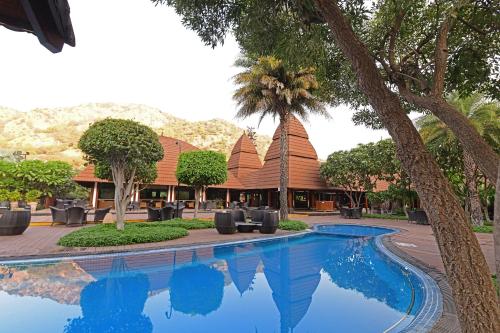 a pool in front of a resort with palm trees at Ananta Spa & Resort, Pushkar in Pushkar