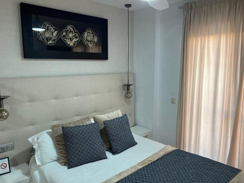 ein Schlafzimmer mit einem weißen Bett mit Kissen in der Unterkunft Apartamento Nemingzhen Tarifa in Tarifa
