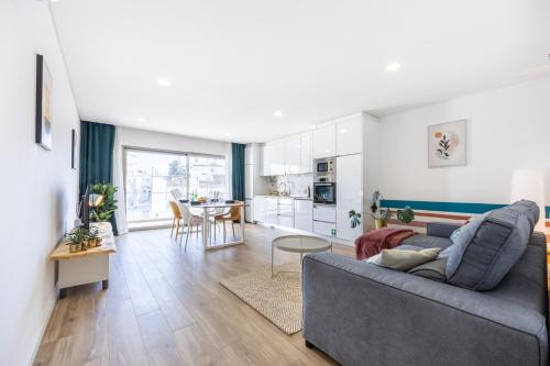 a living room with a gray couch and a kitchen at The Kuuyi Suite in Burgau