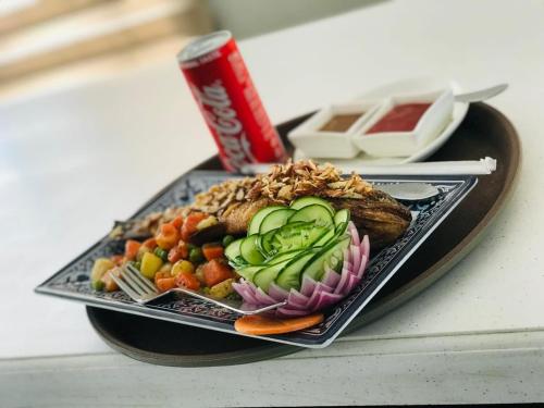 a plate of food on a table with a can of soda at Swat Palace Hotel By Northin in Mām Derai