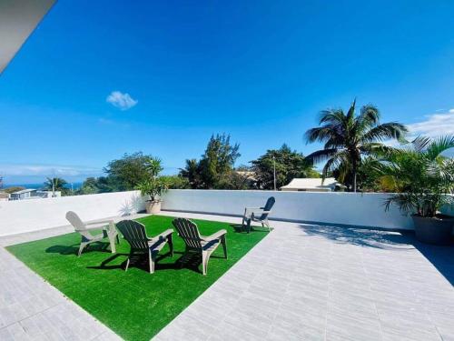 a group of chairs sitting on top of a lawn at Villa Bois de couleur Piscine et Toit Terrasse in Saint-Pierre