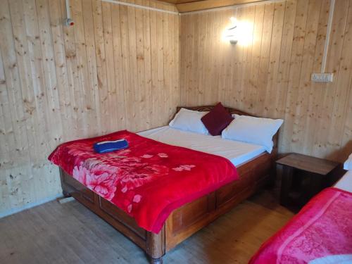 een kleine slaapkamer met een bed met een rode deken bij Snow White Holiday Inn Homestay in Kalimpong