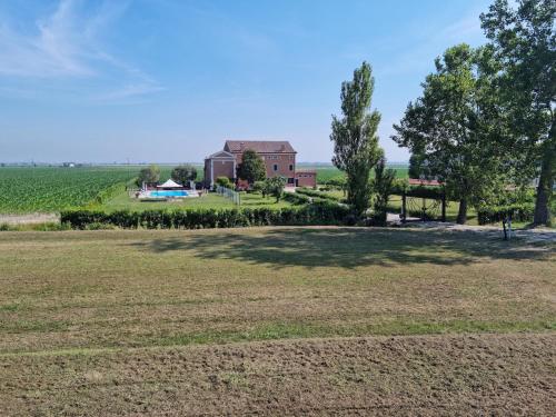 an open field with a barn and trees in the background at Agriturismo Tenuta Goro Veneto in Ariano nel Polesine