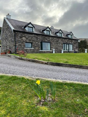 a stone house with a yellow flower in the grass at Valentia View in Portmagee