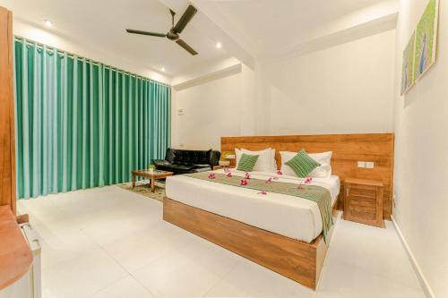 a bedroom with a bed and a green curtain at Kapaliya Unawatuna in Unawatuna