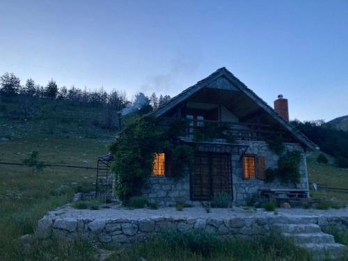 uma pequena casa de pedra com luzes laranja num campo em Mountain house Varda em Ledenice