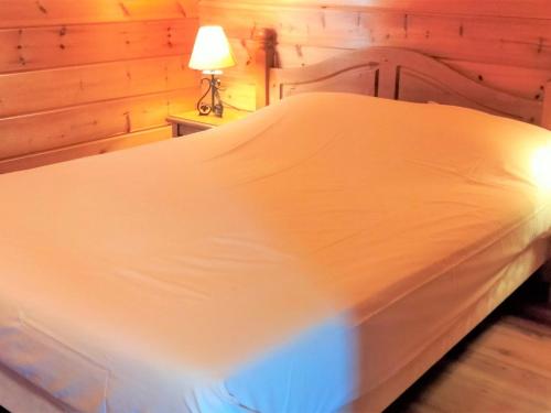 a large white bed in a room with a lamp at Chalet La Joue du Loup, 3 pièces, 6 personnes - FR-1-504-638 in Le Dévoluy