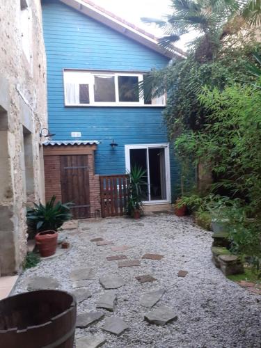 a blue house with a stone path in front of it at Duplex à Samadet in Samadet