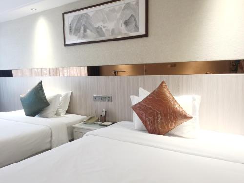 2 letti in camera d'albergo con lenzuola bianche di Paco Hotel Tianhe Coach Terminal Metro Guangzhou a Canton