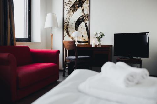 Habitación de hotel con sofá rojo y TV en Vammalan Seurahuone, en Sastamala