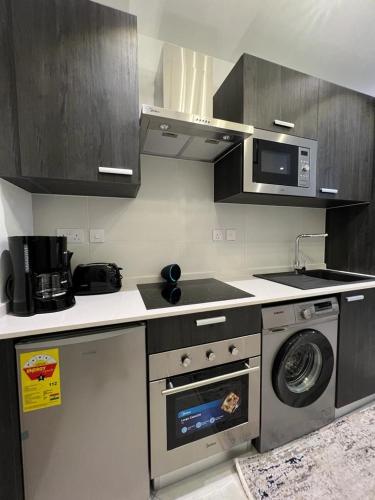 a kitchen with a stove and a washing machine at The Lennox Luxury Apartment in Accra