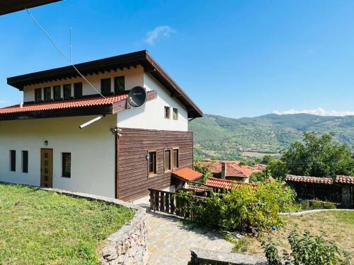 a house on a hill with mountains in the background at Къща за гости Под Манастира in Skrino
