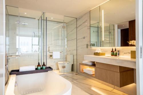 a bathroom with a tub and a glass shower at Crowne Plaza Vinh Yen City Centre by IHG in Yen