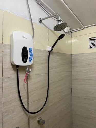 a shower in a bathroom with a hair dryer on a wall at Raihan Beach Resort in Dungun