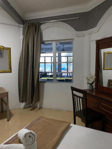a bedroom with a bed and a desk and a window at Raihan Beach Resort in Dungun