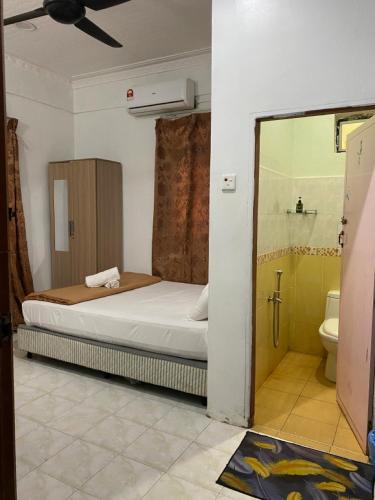 a bedroom with a bed and a bathroom with a toilet at Raihan Beach Resort in Dungun