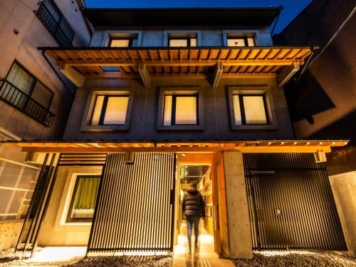 une personne marchant devant un bâtiment dans l'établissement Hale Kyoto Tambaguchi#Tabist, à Kyoto