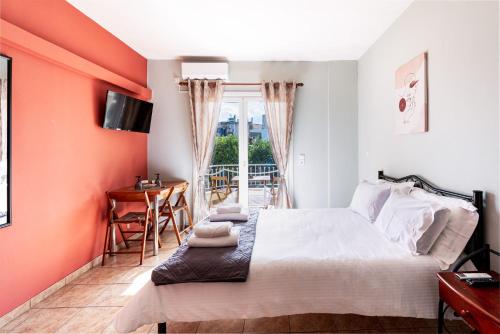 a bedroom with orange walls and a bed and a table at Eagle's Nest - 'Bella' studio flat in Aigio