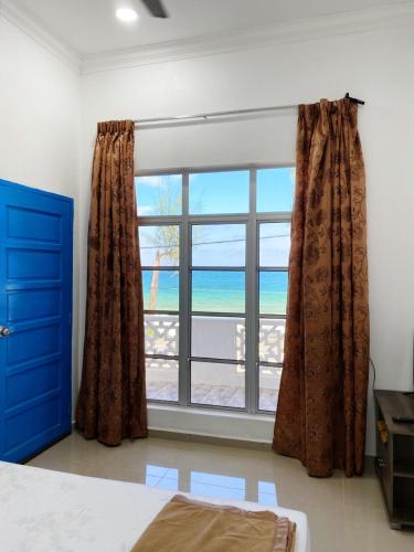 a bedroom with a window with a view of the ocean at Raihan Beach Resort in Dungun
