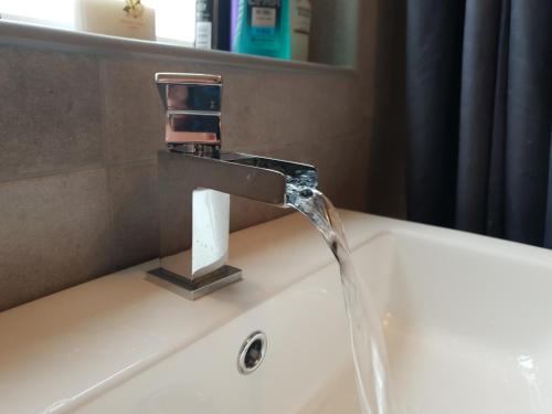 a bathroom sink with water running from a faucet at Redwood House in Liverpool