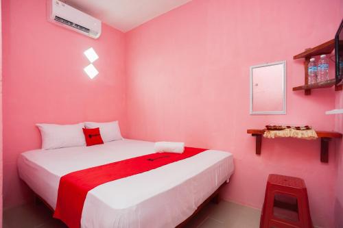 um quarto com paredes cor-de-rosa e uma cama branca em RedDoorz near Simpang Bandara SMB II em Palimbão