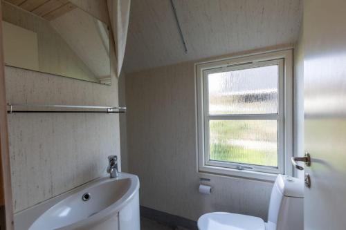 La salle de bains est pourvue de toilettes blanches et d'une fenêtre. dans l'établissement Velling Koller Hotel og Camping, à Bryrup