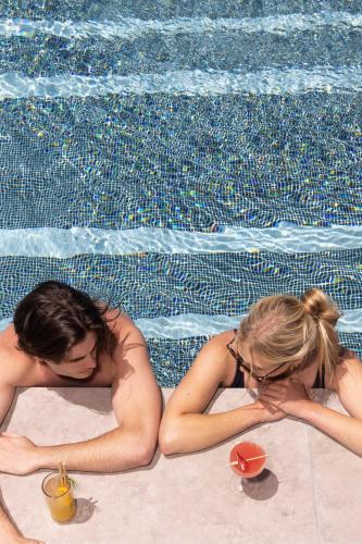 a man and a woman laying next to a swimming pool at Hotel X Brisbane Fortitude Vly, Vignette Collection by IHG in Brisbane