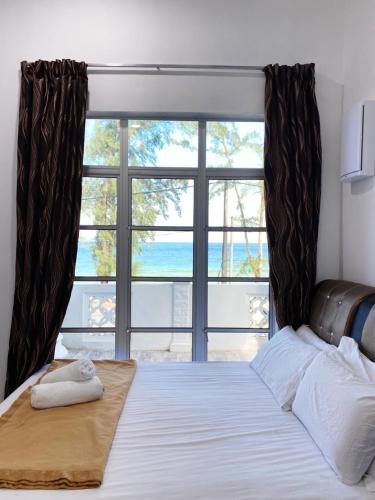 a bedroom with a bed with a large window at Raihan Beach Resort in Dungun