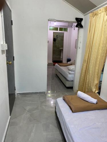 a room with two beds and a hallway with two beds at Raihan Beach Resort in Dungun