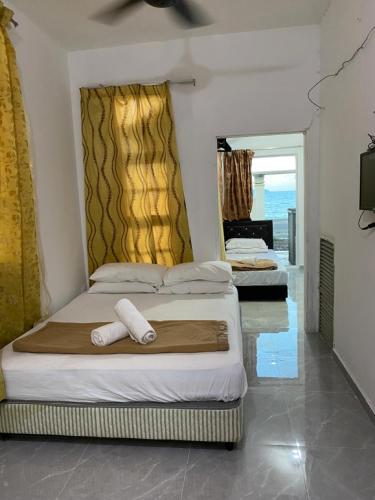 a bedroom with two beds and a view of the ocean at Raihan Beach Resort in Dungun