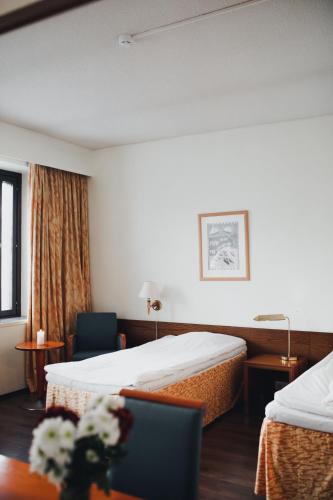 a hotel room with two beds and a chair at Hotel Tunneli in Sastamala