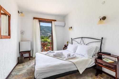 a bedroom with a bed with white sheets and a window at Amalia2 in Skopelos Town