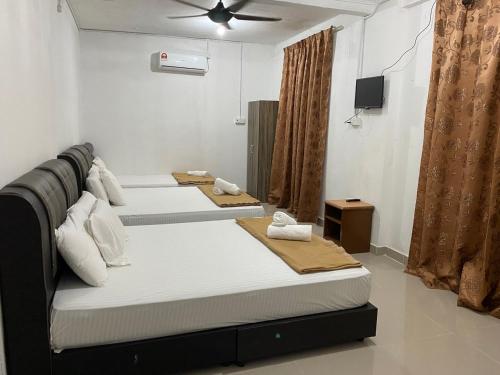a room with three beds and a television in it at Raihan Beach Resort in Dungun