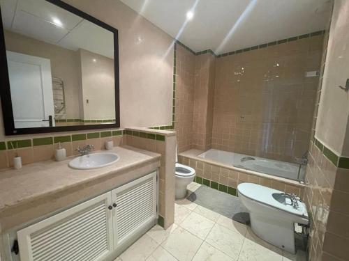 uma casa de banho com um lavatório, um WC e um espelho. em Stunning house in La Reserva Golf Course em Sotogrande