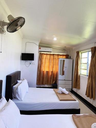 a small bedroom with two beds and a refrigerator at Raihan Beach Resort in Dungun