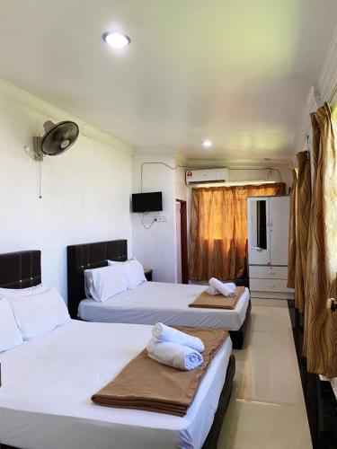 a bedroom with two beds with towels on them at Raihan Beach Resort in Dungun