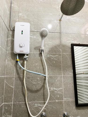 a blow dryer on the wall of a shower at Raihan Beach Resort in Dungun