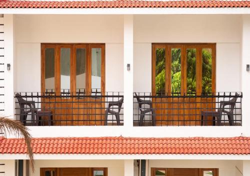 a white building with windows and chairs on a balcony at The Verda De Miranda Resort Morjim North Goa in Morjim