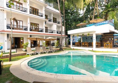 a swimming pool in front of a building at The Verda De Miranda Resort Morjim North Goa in Morjim