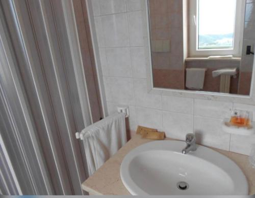 La salle de bains est pourvue d'un lavabo blanc et d'un miroir. dans l'établissement Santangelo Hotel, à Monte SantʼAngelo