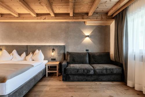 a hotel room with a bed and a couch at Hotel Niblea Dolomites in Ortisei