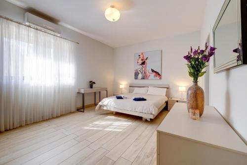a bedroom with a bed and a vase of flowers at Stylish 3 Bedroom Holiday Apartment in St Julians in St Julian's